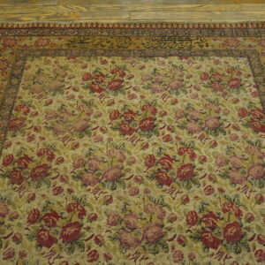 Low pile tan rug featuring an all-over red and pink floral pattern with border calligraphy.