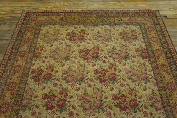 Low pile tan rug featuring an all-over red and pink floral pattern with border calligraphy.