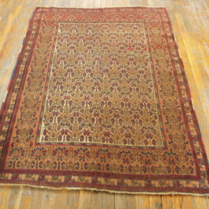 A rust and tan patterned rug with a detailed border sits on wide, distressed wooden flooring.