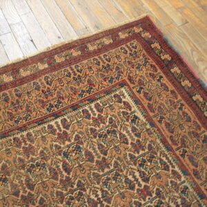 Low-pile rug in tan, blue, and red geometric pattern featuring detailed multiple borders on wood planks.