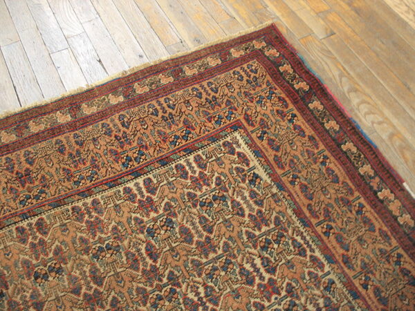 Low-pile rug in tan, blue, and red geometric pattern featuring detailed multiple borders on wood planks.