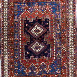 Multicolored geometric rug with a detailed navy center medallion surrounded by red and blue patterned borders.