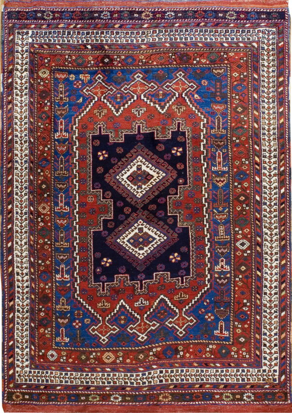 Multicolored geometric rug with a detailed navy center medallion surrounded by red and blue patterned borders.