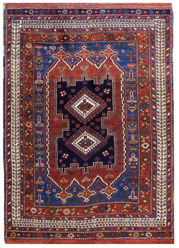 Geometric rug in navy, bright blue, and rust red, featuring a centralized diamond design and complex borders.