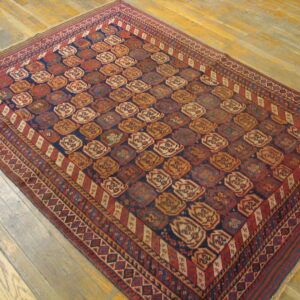 A rectangular dark blue and rust-red geometric rug displayed on light natural wood floors.