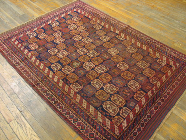A rectangular dark blue and rust-red geometric rug displayed on light natural wood floors.