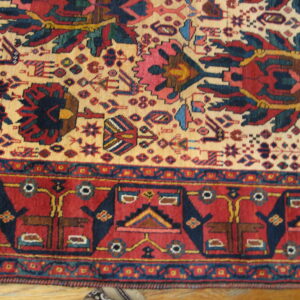 Red, navy, and cream tribal rug detail showing stylized motifs and geometric borders on wood.