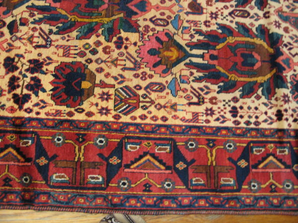 Red, navy, and cream tribal rug detail showing stylized motifs and geometric borders on wood.