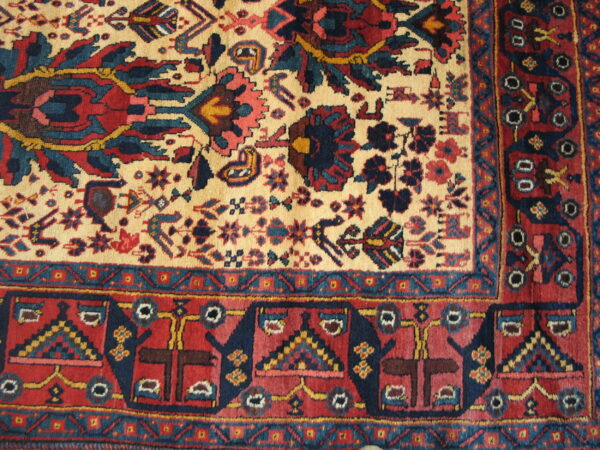 Detail of a traditional rug featuring a high pile and complex red, navy, and cream floral and geometric patterns.