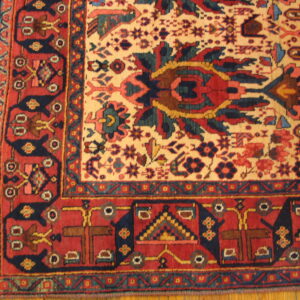 Red and cream rug with navy geometric motifs and short fringe rests on a polished wooden floor.