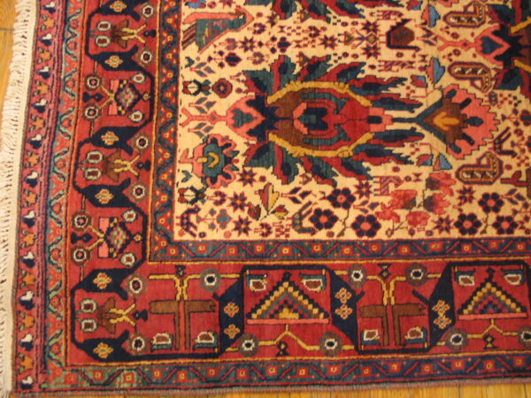 Red and cream rug with navy geometric motifs and short fringe rests on a polished wooden floor.