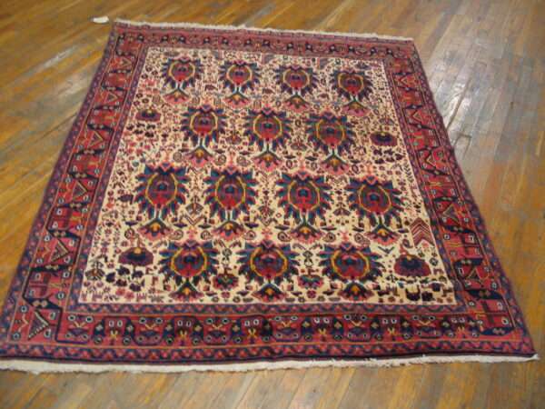 Low-pile rug features red borders and a cream field with navy and red repeating medallions on wood flooring.