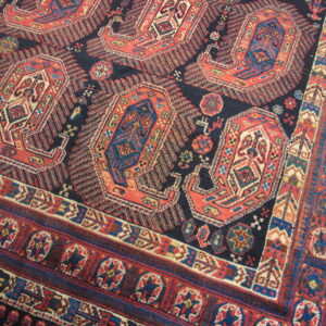 Geometric rug with large red and blue medallions on a navy field and intricate, multi-banded borders.