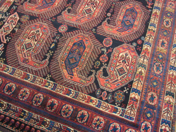 Geometric rug with large red and blue medallions on a navy field and intricate, multi-banded borders.