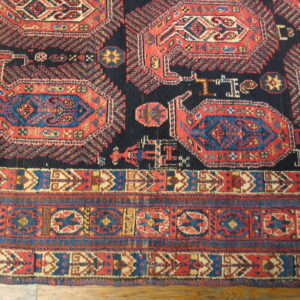 Red, navy, and blue geometric rug featuring traditional medallions and complex borders resting on a light brown wood floor.