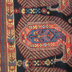 Geometric rug pattern featuring a navy field, a red and blue central motif, and complex multicolored borders.