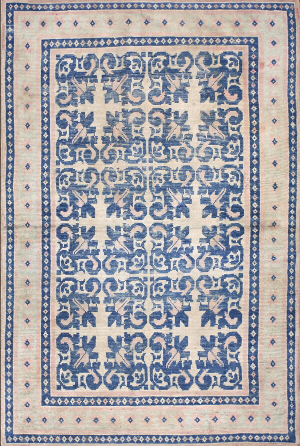 Cream rug with a bold blue and pink repeating geometric floral design and multiple borders.