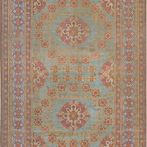 Muted blue field rug with salmon and purple floral medallions surrounded by intricate geometric borders.