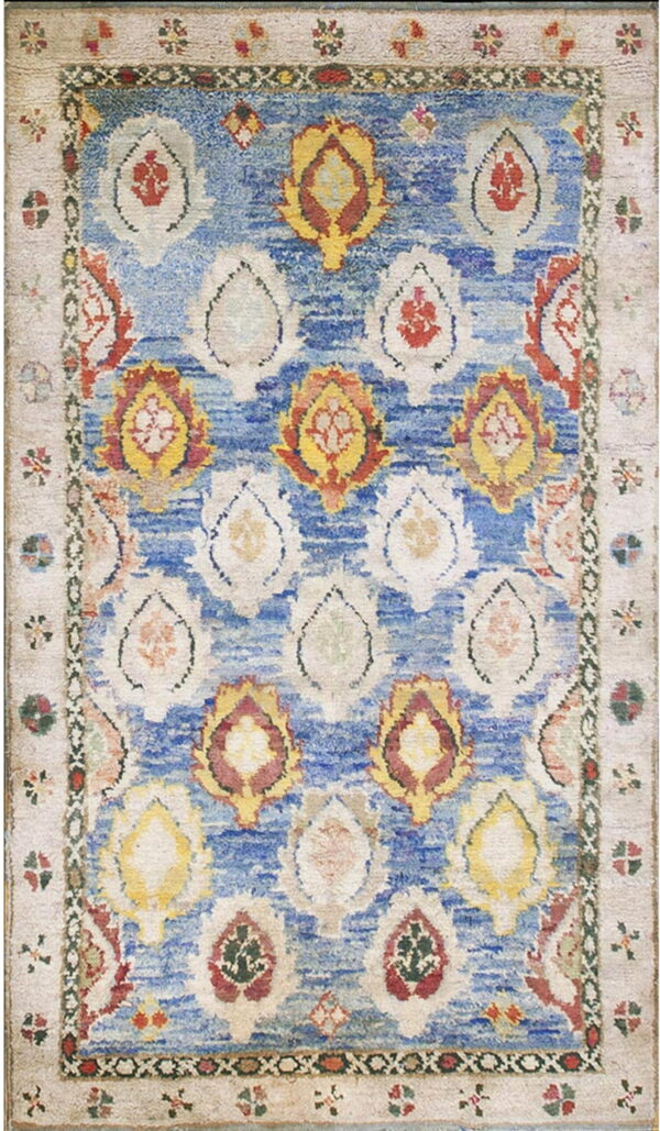 Textured rug with a vibrant blue field featuring distressed repeating medallions in ivory, red, and yellow.