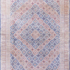 Muted rug with a pale beige border surrounding a field of blue and red geometric diamonds.