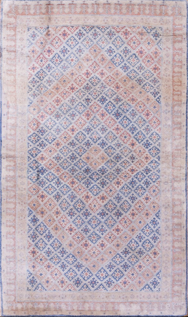 Muted rug with a pale beige border surrounding a field of blue and red geometric diamonds.