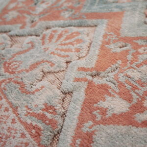 Intricate plush rug featuring carved coral, sage blue, and cream motifs with high and low pile.