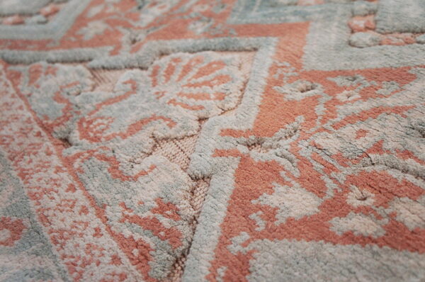 Intricate plush rug featuring carved coral, sage blue, and cream motifs with high and low pile.