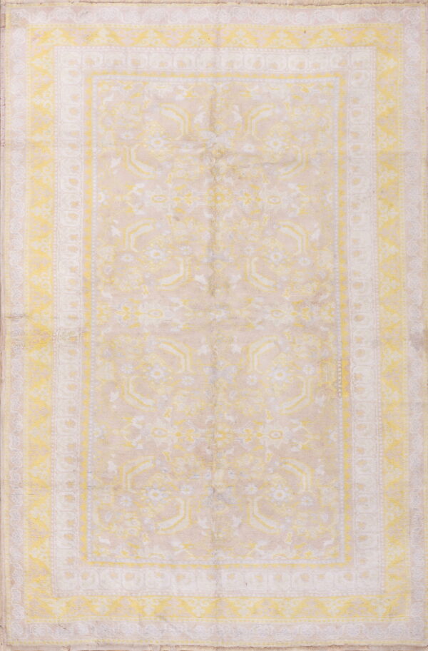 Rectangular, low-pile rug displaying faded traditional motifs and borders in yellow and light beige.