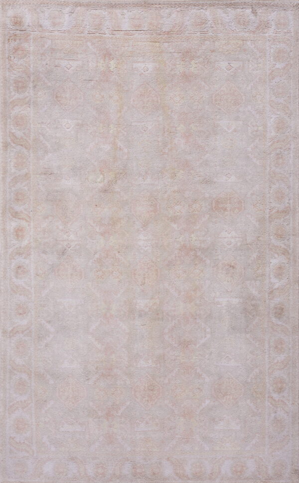 Low-pile rug with faint traditional designs, featuring neutral cream and light blush colors.