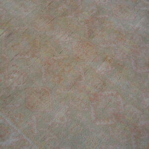 Distressed rug surface in muted gray and faded pink colors showing a low-contrast traditional pattern.