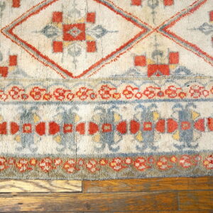Geometric ivory, terracotta, and dusty blue high-pile rug detail shown on hardwood flooring.
