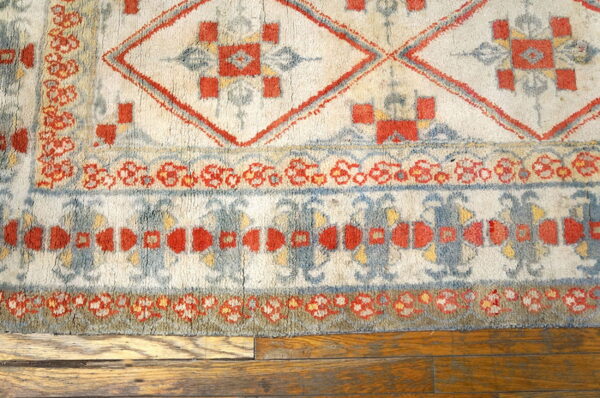 Geometric ivory, terracotta, and dusty blue high-pile rug detail shown on hardwood flooring.