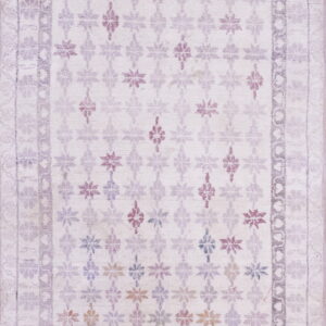 Washed pale lavender rug featuring a geometric floral pattern field with small multicolored accents and bordered edges.