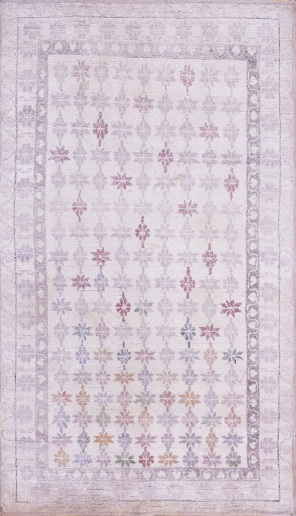 Washed pale lavender rug featuring a geometric floral pattern field with small multicolored accents and bordered edges.