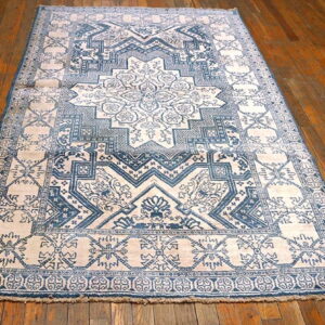 Blue and light patterned rug with a traditional medallion design on shiny brown wood floors.