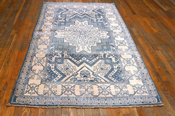 Blue and light patterned rug with a traditional medallion design on shiny brown wood floors.