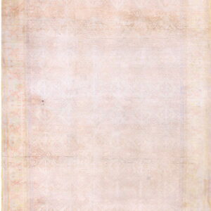 Faint geometric patterns cover this low-pile rug in muted blush and cream tones.