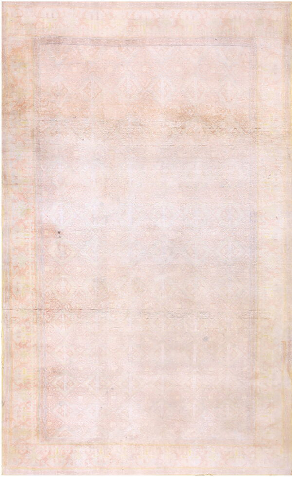 Faint geometric patterns cover this low-pile rug in muted blush and cream tones.