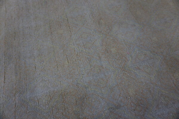 Textured, low-pile rug featuring a subtle, faded abstract pattern in gray, slate, and tan colors.