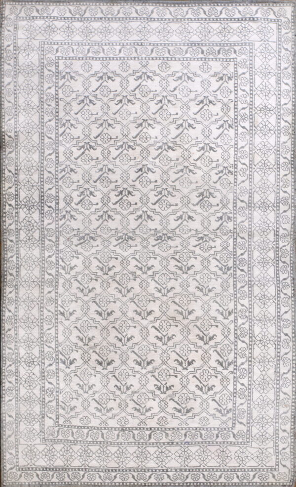 Monochromatic rug with intricate gray geometric and floral patterns covering a light off-white field.