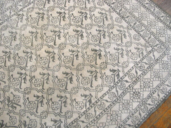 Geometric tribal pattern in gray on a cream ground, showing multiple patterned borders on wood floor.