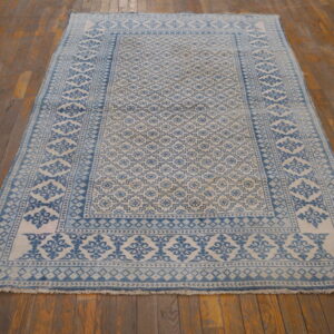 Rectangular low-pile rug in blue and cream geometric designs placed on worn wood planks.