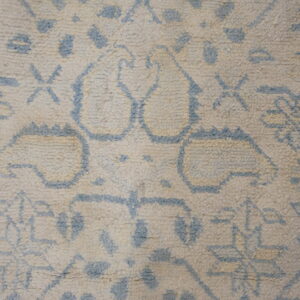 Detail of a shaggy rug featuring blue outline patterns over a thick, creamy beige pile.