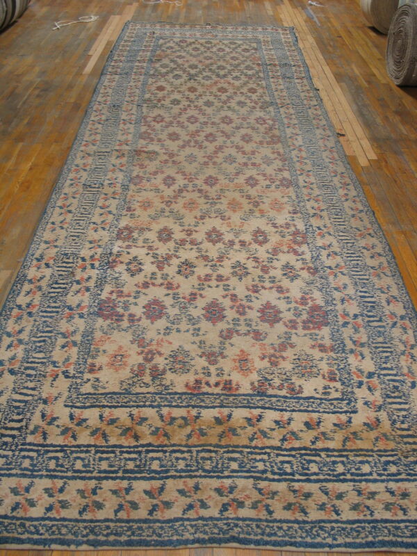 A large distressed runner with blue and rust floral motifs lies on a varnished wood floor.