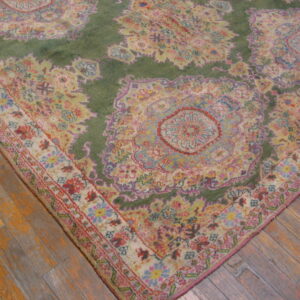A high-pile rug featuring ornate green and pastel floral medallions rests on rustic wood flooring.
