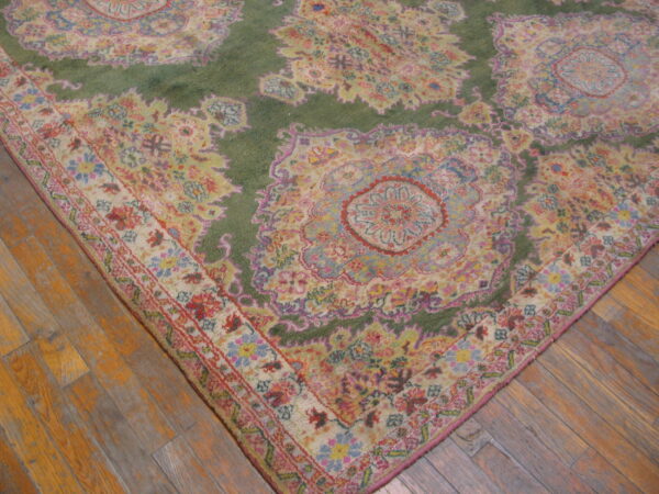 A high-pile rug featuring ornate green and pastel floral medallions rests on rustic wood flooring.