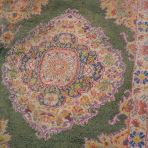 Shaggy rug featuring a vibrant medallion pattern in pink, yellow, blue, and cream on a moss green field.