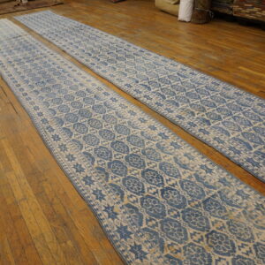 Two long blue and cream geometric patterned runners lie parallel on the worn wooden floor.