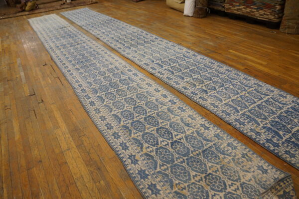 Two long blue and cream geometric patterned runners lie parallel on the worn wooden floor.