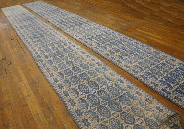 Two long blue and beige runners with a distressed medallion pattern lie parallel on a wood plank floor.